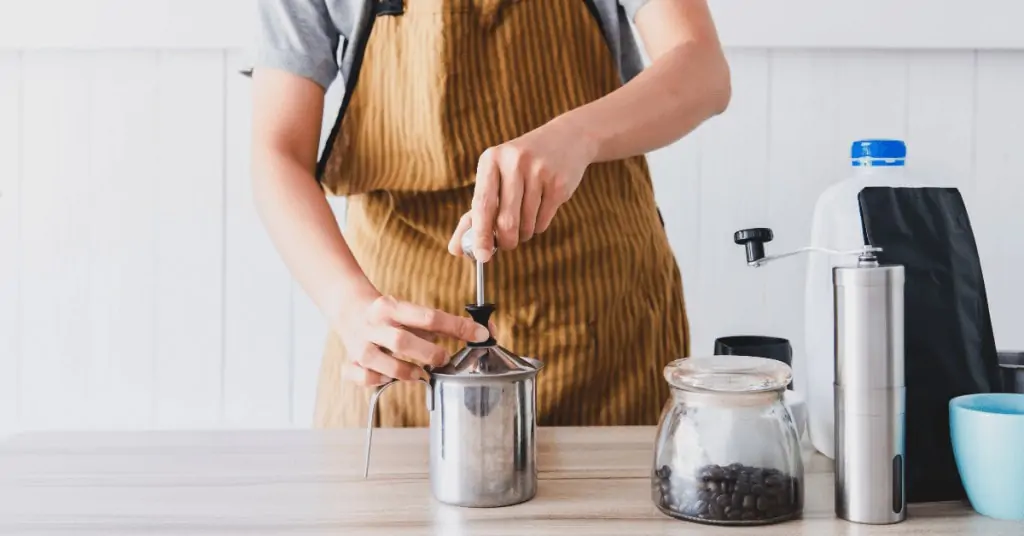 man using manual milk frother