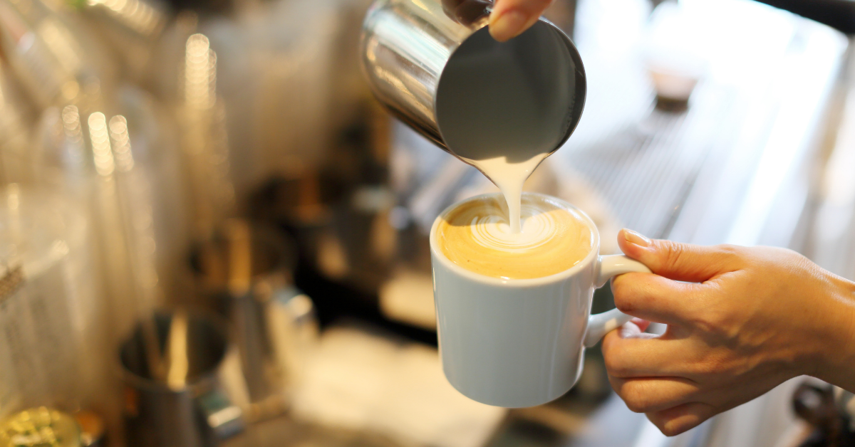 a person pouring milk in coffee