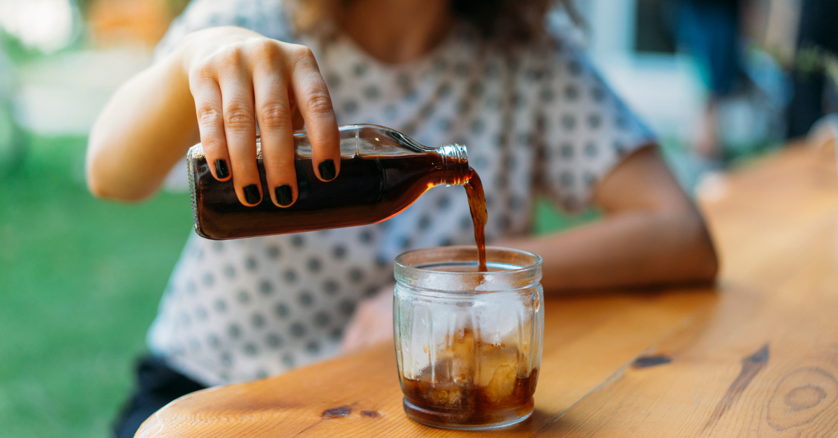 a woman pouring cold brew espresso in a glass