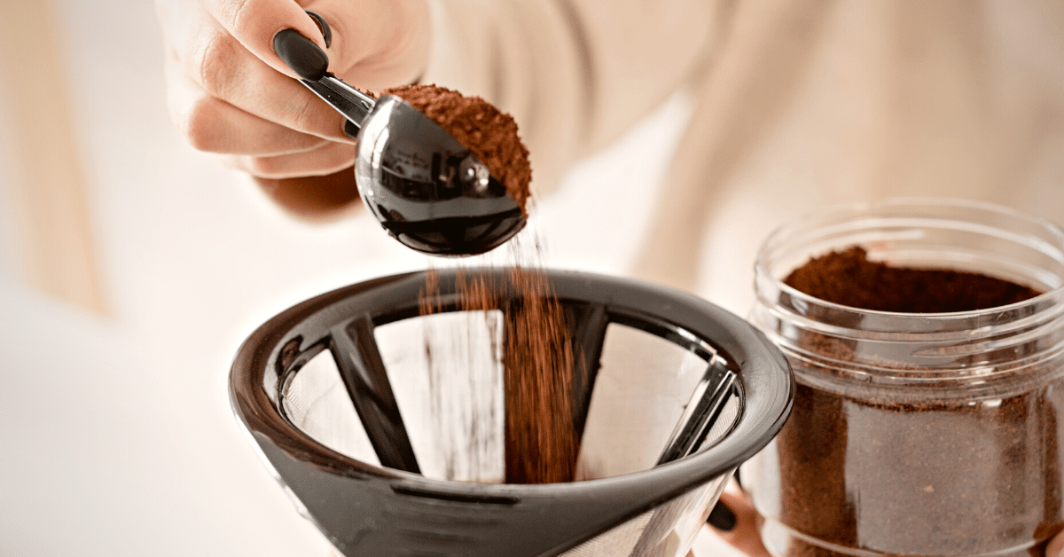 woman pouring grinded coffee beans in chemex