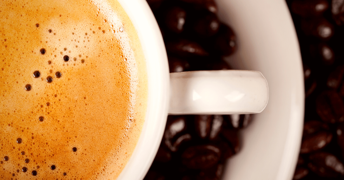 coffee in a cup and dark roast beans on plate