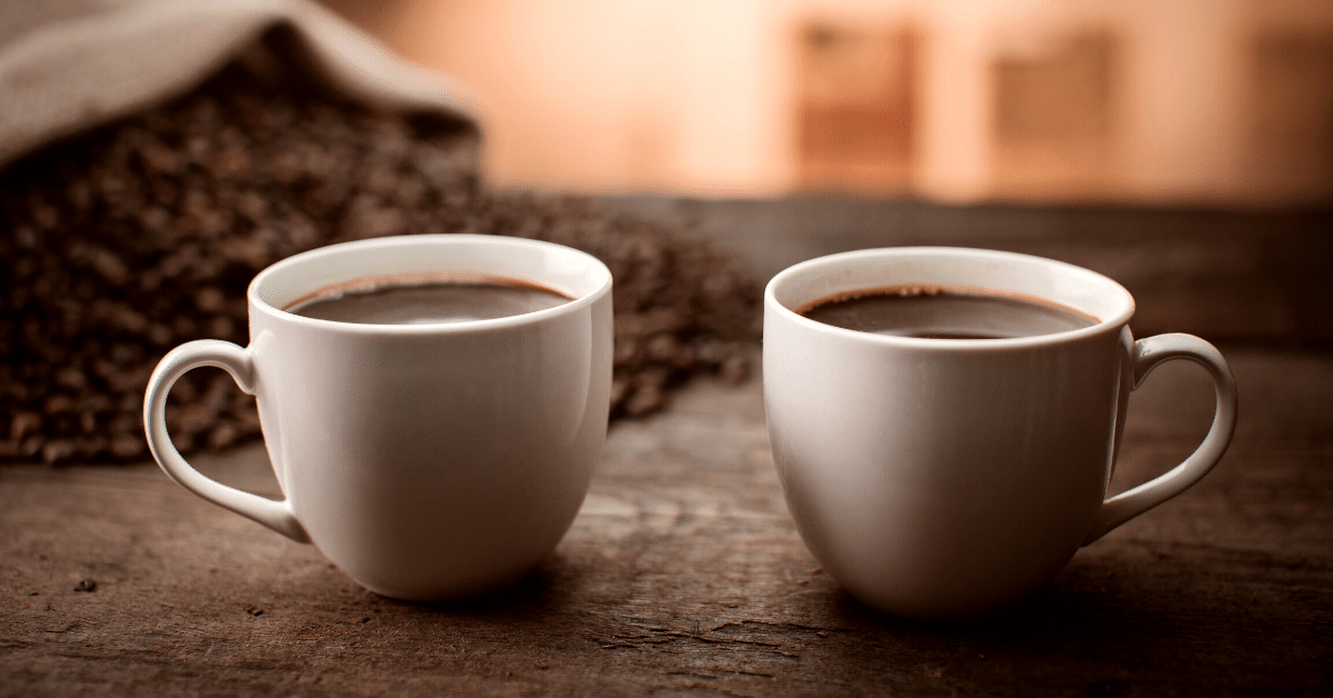 two cups of coffee beside coffee beans