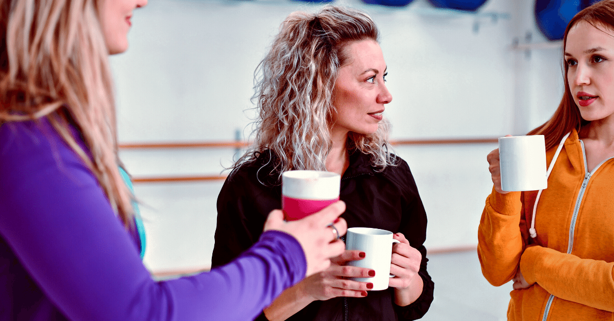 three women drinking coffee before a workout