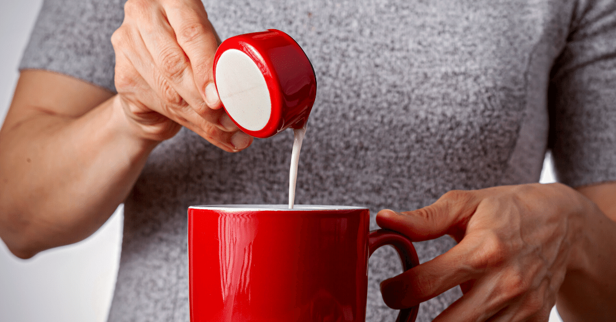 person adding creamer to coffee