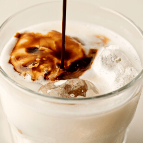 pouring coffee in glass with milk