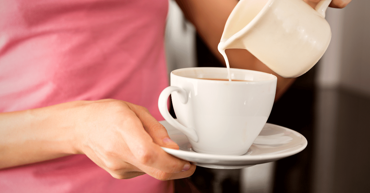 woman adding milk to her coffee