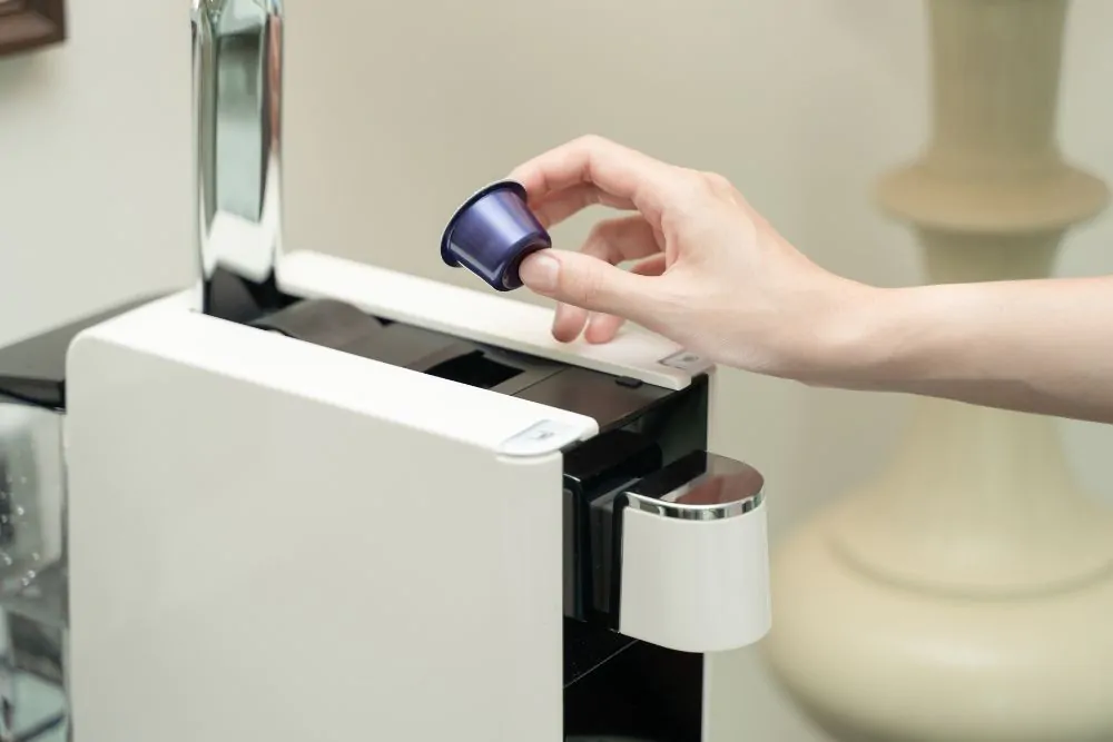 hand putting coffee capsule into a coffee maker